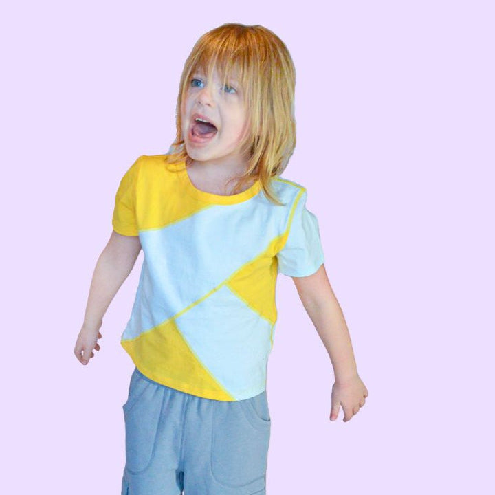 Child standing on a balance board against a pink background in sensory clothing